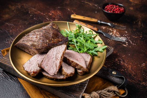 Roasted smoked Tri Tip or sirloin bottom beef steak dinner on a plate with arugula.